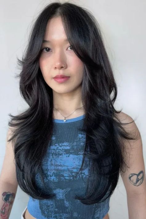 Person with long, layered black hair and tattoos on arms, wearing a blue tank top. Wolf Cut Girls Long Hair, Mid Length Wolf Cut Straight Hair, Wolf Cut Hair Styling, Wolfcut Mid Length, Wolf Cut On Straight Hair, Wolf Tail Haircut, Wolf Cut Side Part, The Wolf Cut Hair, Wolf Cut Short