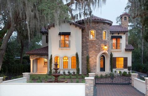 This stunning 2 story Mediterranean house is well put together with a white stucco exterior walls, a round tower brick entrance, arched windows, and a beautiful black arched entry door. Mediterranean Homes Exterior, Mediterranean Exterior, Mediterranean Mansion, Mediterranean House, Mediterranean Style Homes, Stucco Exterior, Mediterranean Home Decor, Casas Coloniales, Spanish Style Homes