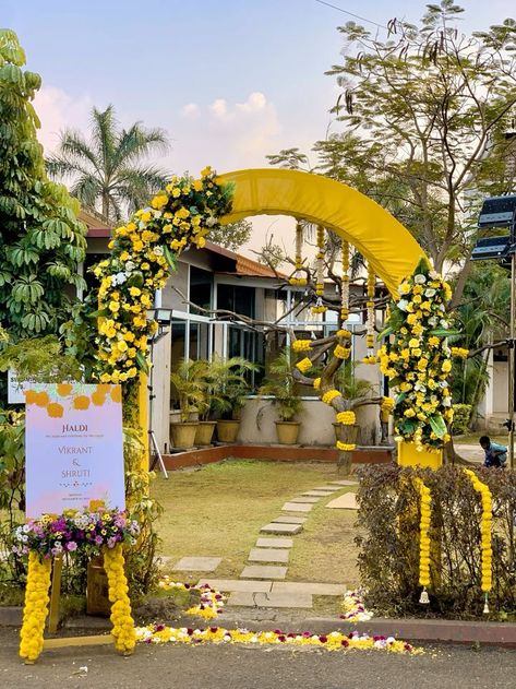 If you’re fortunate enough to have a lush backyard, transform it into a vibrant and whimsical Haldi celebration venue. Incorporate hanging props, dreamcatchers, colorful sofas, and vintage lighting to create a truly enchanting and Instagram-worthy setup. Haldi Ka Decoration, Haldi Entrance Decoration Ideas, Haldi Arch Decor, Haldi Entry Gate Decor, Entry Door Flower Decoration, Haldi Backdrop Ideas, Haldi Gate Decoration, Entry Gate For Wedding, Simple Haldi Decor