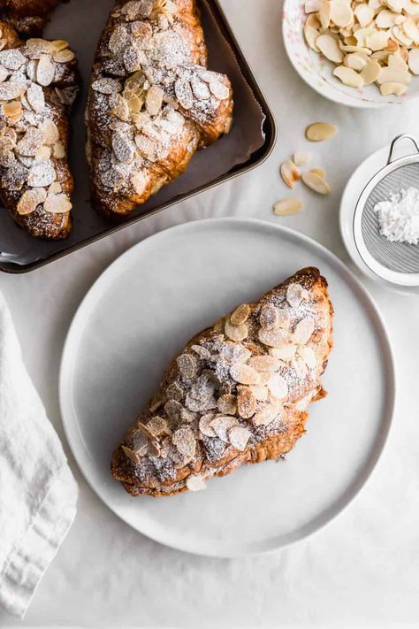 Almond croissant on a white round plate with tray of almond croissants on a tray, flaked almonds scattered around. Chocolate Croissant Recipe Easy, Croissant Recipe Easy, Kids Birthday Breakfast, Almond Croissant Recipe, Chocolate Croissant Recipe, Almond Croissants, Mini Croissants, Croissant Recipe, Almond Croissant