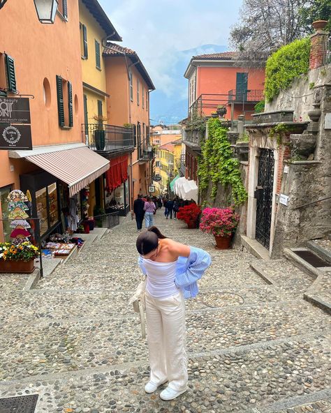 A girl standing in a narrow street in Bellagio, lake Como - Italy. Spring time. Lake Como Outfit, Linen Trousers Outfit, Blue Top Outfit, Blue Linen Trousers, Lake Outfit, France Outfits, Trousers White, Italy Summer, White Stripes Shirt