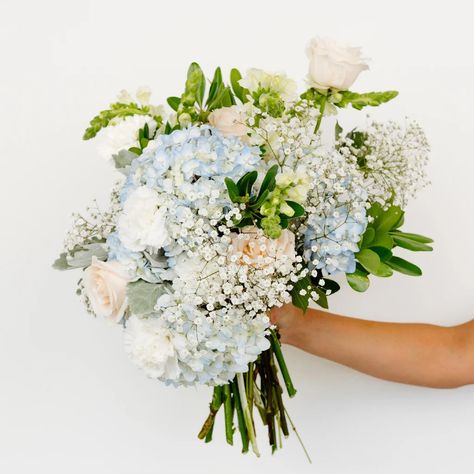 Create some beachy blues with our Coastal Vibes Hydrangea Flower Pack. This pack features beautiful blue blooms like hydrangeas and delphinium paired with whites such as roses and snapdragons. To add a soft foamy look, this DIY flower combo also includes Dusty Miller greenery. Use this pack to create a blue baby shower, or for a beach wedding. However you decide to use this pack, it will make you feel like you're walking right on the beach! Blue Wedding Hydrangea, Hydrangea Flower Arrangements Wedding, Blue Floral Arrangements Wedding, Blue And White Hydrangea Centerpiece, Blue Prom Flowers, Wedding With Hydrangeas, Light Blue Flower Bouquet, Dusty Blue Hydrangea, Hoco Bouquet