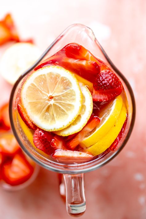 An overhead picture of a pitcher of pink lemonade sangria. Lemonade Sangria, Pitcher Cocktails, Kid Friendly Drinks, Blush Wine, Strawberry Wine, Lemon Lime Soda, Dirty Dishes, Sprinklers, Lemon Slice