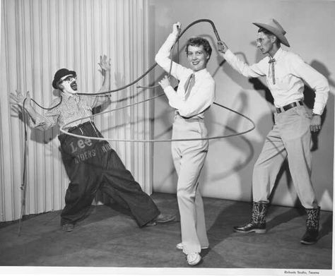 1954 Western circus acts. Three people demonstrate individual Western circus skills in an August 30, 1954, studio photograph. A trick rope artist seems to suspend her rope in the air around her body while a man in cowboy hat and boots lashes his whip across the neck of a startled clown. Man In Cowboy Hat, Cowboy Ring, Trick Roping, Circus Acts, Old Soul, Cowboy Hat, Circus, Cowboy Hats, A Man