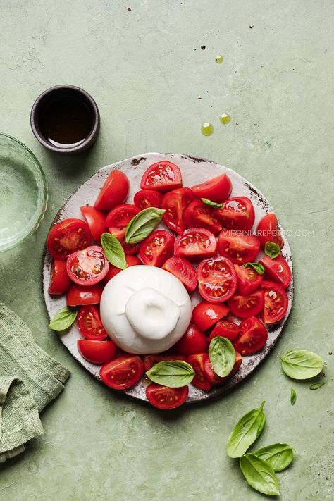 Tomato and burrata salad with fresh basil leaves on a green backdrop- Minimalism in food photography Salads Photography Styling, Tomato Salad Photography, Italian Food Styling Photography, Tomato Photography Food Styling, Editorial Food Photography, Salad Photography Food Styling, Fruit Salad Photography, Minimalist Food Photography, Tomato And Burrata