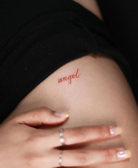 Tattoo of the word "angel" in red ink located on the Red Tattoo Writing, Red Angel Wings Tattoo, Word Angel Tattoo, Red Angel Tattoo, Red Ink Word Tattoo, Angel Tattoo Word, Red Ink Neck Tattoo, Angel Word Tattoo, Angel Name Tattoo