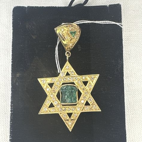 This stunning pendant is a must-have for any jewelry lover. Crafted from 18k yellow gold, it features a beautiful emerald stone with a star shape. The pendant is designed in the shape of the Star of David, making it a unique piece of jewelry with a Jewish heritage. The pendant is adorned with sparkling diamonds, which add an extra level of elegance to this piece. The emerald stone is of high quality, and its rich green color is sure to catch the eye. This pendant is perfect for any occasion, whe