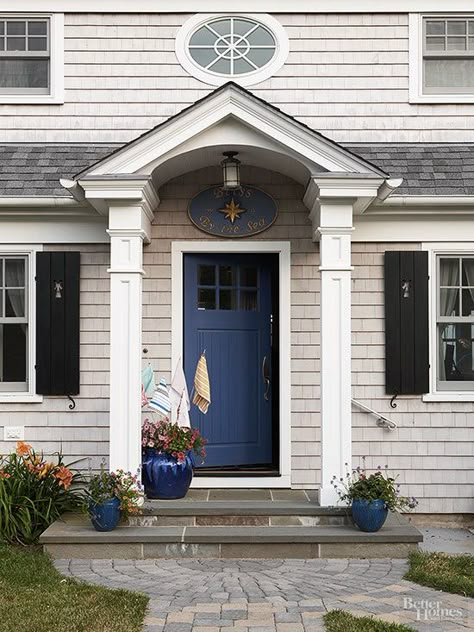 Framed by roof-supporting columns, this front door demanded notice. The homeowners referenced their coastal locale by painting the door a deep-sea blue that pops against the home's siding and trim. Vividly glazed containers and blue-toned pavers carry the door's hue further into the landscape. Cottage Style Front Doors, Cottage Front Doors, Best Front Doors, Blue Front Door, Front Door Paint Colors, Door Paint Colors, Painted Front Doors, Casa Exterior, Front Door Colors