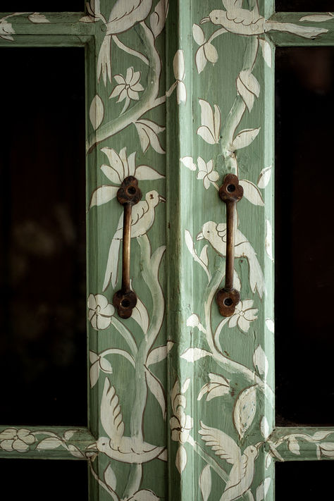 A masterpiece of craftsmanship and design collaboration, the Birdie pieces feature a delicate scene depicting birds and vines, designed in-house and beautifully executed in India. Featuring a hand painted pattern atop HMcG colour Hampstead Green, glazed double doors with antique gold hardware, charming saber legs, three shelves and original teak interior. #handpainted #antiquefurniture #rusticfurniture #furnituredetails #brasshardware #greenfurniture Diy Paint Wardrobe, Painted Cabinet Interior, Diy House Paint Interior, Hand Painted Doors Ideas, Pattern On Pattern Interior Design, Green Painted Furniture Ideas, Mushroom Painted Furniture, Antique Interior Doors, Yellow Green Interior Design