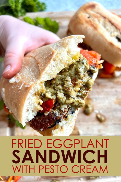 Two halves of a Fried Eggplant Sandwich with Pesto Cream, one half held toward the camera by a hand Breaded Eggplant Sandwich, Eggplant Panini Recipes, Artichoke Parm Sandwich, Eggplant Pesto Recipes, Roasted Eggplant Sandwich, Fried Eggplant Sandwich, Eggplant Sandwich Recipes, Poolside Sandwiches, Eggplant Parm Sandwich