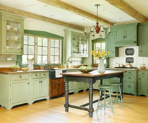 Antique-furniture-style cabinets and a farm table island stamp this kitchen with country charm. The brand-new, custom-built cabinets are heavily distressed to look as if layers of paint had been applied to them over many years. And intentionally unmatched colors of mossy-greens and woodsy-browns give the appearance that this kitchen might have been added to or changed over the years. Beveled moldings and ledge accents give standard upper cabinets a vintage-cupboard look, reinforcing the farmh... Dapur Rustic, Witchy Cottage, Green Kitchen Designs, Model Dapur, Cottage Decorating, Amazing Homes, Kabinet Dapur, Country Kitchens, Green Kitchen Cabinets