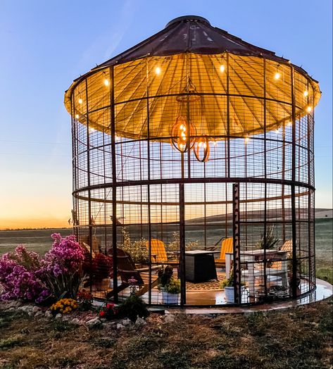 This corn crib gazebo is a beautiful farmhouse inspired space ready for outdoor entertaining. A barrel ring light fixture adds interest with adirondack chairs and a fire pit ready to keep you warm or to make up some s’mores for your guests. Farmhouse Gazebo Ideas, Gazebo In Front Of House, Silo Fire Pit Ideas, Corn Bin Ideas, Farmhouse Gazebo, Silo Gazebo Backyards, Grain Bin Fire Pit Outdoor Fireplaces, Grain Bin Fire Pit, Corncrib Gazebo Ideas