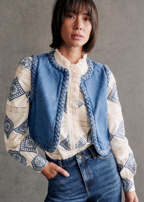 The Sézane Abby Veste is a short, sleeveless denim jacket that combines casual style with unique details. Adorned with decorative braids around the armholes and jacket edges, this piece adds a touch of creativity to your outfit. Perfect for layering over a simple tee or a blouse, it’s a chic way to embrace effortless Parisian flair. Discover more at sezane.com or via the app.​ Denim Style Casual, Winter Mini Dresses, Chaleco Casual, Moda Denim, Blue Vest, Denim Quilt, Sleeveless Outfit, Denim Patterns, Mini Robes