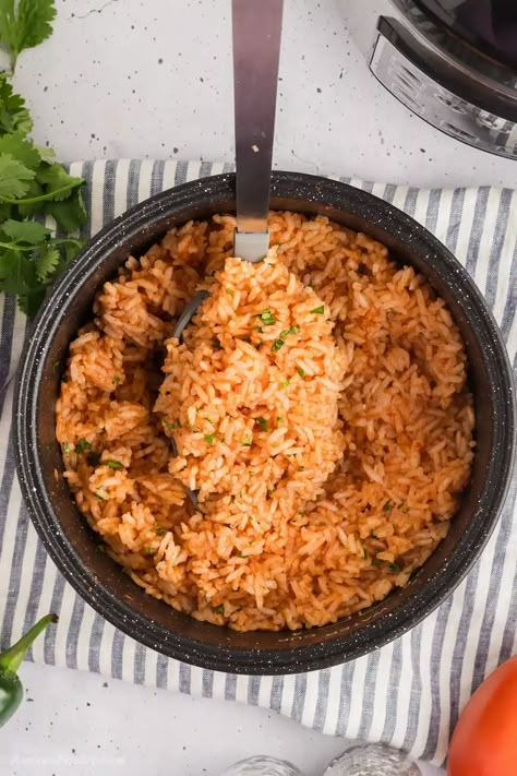 A spoon scooping some Mexican rice from a rice cooker. Rice Cooker Spanish Rice Easy, Mexican Rice Rice Cooker, Spanish Rice In Rice Cooker, Mexican Rice In Rice Cooker, Mexican Rice Recipe Rice Cooker, Rice Cooker Spanish Rice, Rice Cooker Mexican Rice, Aroma Rice Cooker, Mexican Rice Recipe