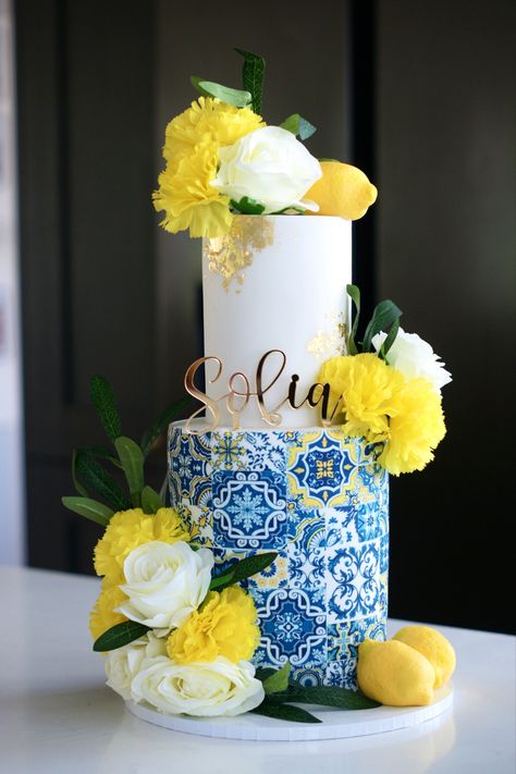 Blue Mediterranean tiles, two tier birthday cake, sugar lemons, yellow flowers, edible gold leaf, gold acrylic topper, Amalfi themed cake Blue Tiles And Lemons Theme, Greece Themed Cakes, Lemon Theme Cake Ideas, Amalfi Theme Cake, Birthday Cake Lemon Theme, Amalfi Coast Theme Cake, Amalfi Birthday Theme, Italian Lemon Theme Party, Amalfi Coast Birthday Theme