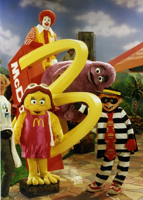 Ronald McDonald, Birdie the Early Bird, Grimace and Hamburglar in the 1993 International McDonaldland commercial called "GROWING M".  The characters plant a small golden arch in the ground, and grow an entire McDonald's Restaurant. Mcdonald Land, Mcdonald Costume, Ronald Mcdonald Costume, Mcdonalds Restaurant, Mcdonald's Aesthetic, Mcdonalds Birthday Party, Golden Arch, Mcdonalds Gift Card, Mcdonald's Restaurant