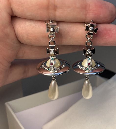 This item is pre-owned in a great condition, like new. Please do not purchase if this will bother you.  Revisiting Vivienne Westwood's iconic collection, dating back decades indulge in the glamorous and instantly recognisable Pearl Drop Earrings. Detailed with signature Westwood Orb beautifully adorned with multi coloured Swarovski crystals, the earrings are finished with a sophisticated pearl drop, perfected in silver-tone plated brass. Earring measurements: approx drop 5.5cm. Orb is approx 2.5cm W,2.5cm H. Come with Vivienne Westwood dustbag:) Vivienne Westwood Dangle Earrings, Vivienne Westwood Drop Earrings, Vivienne Westwood Ariella Earrings, Vivienne Westwood Wedding Ring, Vivienne Westwood Pearl Earrings, Aesthetic Vivienne Westwood, Viviane Westwood, Vivienne Westwood Wedding, Vivienne Westwood Earrings