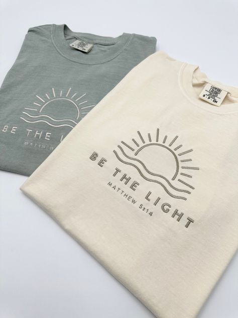 Embroidered Be The Light Matthew 5:14 Comfort Colors® Shirt | Inspirational Christian Tee | Religious Faith Clothing | Bible Verse Gifts The item in the first picture features Cream thread color on a Pepper Comfort Colors T-shirt. The item in the first picture features Sand thread color on a Bay Comfort Colors T-shirt. The item in the first picture features Doe Skin Beige thread color on an Ivory Comfort Colors T-shirt. The item in the first picture features Cream thread color on a Yam Comfort C Cute Spring Shirts, Unisex Christian Shirt Ideas, Simple Christian Shirt Designs, Aesthetic Christian T Shirts, Cute Mission Fits, Cute Jesus Shirts, Cute Christian T Shirts, Christian Tshirt Design Ideas Vinyl, Cricket Projects Craft Ideas Shirts