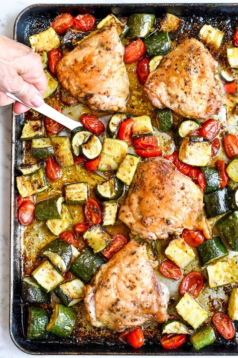 In this delicious summery sheet pan dinner chicken thighs are seasoned with garlic and herbs and roasted with tender chunks of zucchini and cherry tomatoes that caramelize as they cook. The fresh basil sprinkled on just before serving enhances the summer tastes. This meal is gluten free, paleo and incredibly simple. Sheet Pan Dinners With Cherry Tomatoes, Chicken Zucchini And Tomato Recipes, Sheet Pan Chicken And Tomatoes, Chicken Thigh Recipes Zucchini, Zucchini And Cherry Tomato Recipes, Sheet Pan Chicken And Zucchini, Boneless Skinless Chicken Thigh Sheet Pan Dinner, Chicken Thighs Sheet Pan Dinner, Chicken Thighs And Zucchini Recipes