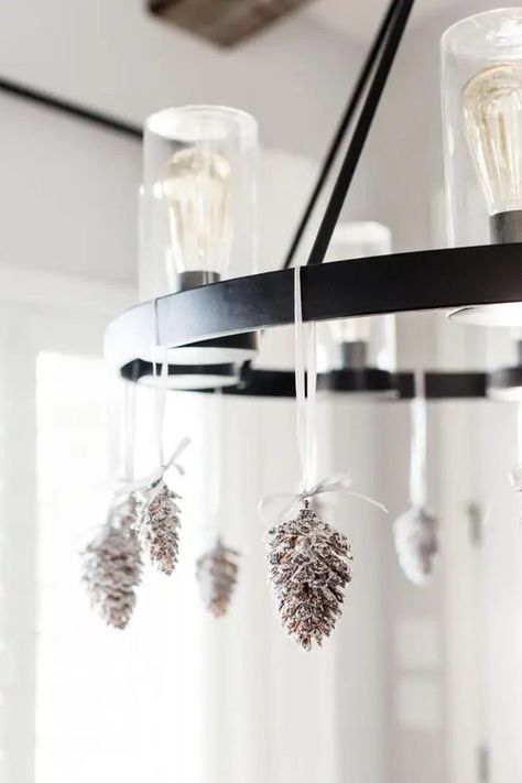 a bulb chandelier decorated with snowy pinecones is a cool and chic idea for the holidays, it's quite rustic Decorating A Chandelier, Zellige Tile Bathroom, Christmas Chandeliers, Christmas Chandelier Decor, Snowy Pinecone, Black Interior Door, Christmas Chandelier, Bulb Chandelier, Bathroom Chandelier