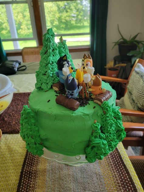 Bluey camping birthday cake with green frosting, waffle cone trees and a campfire of pretzels and birthday candles. Bluey Camping Cake, Bluey Camping, Camping Birthday Cake, Campfire Birthday, Camping Cake, Camp Birthday, Camping Cakes, Bluey Party, Birthday Sheet Cakes