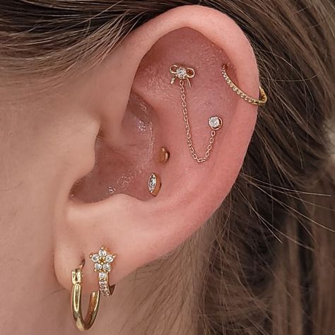 We’re tied up in the beauty of this ear curation! 🎀  Ear curation by @piercedemerald  Flat piercing with a gem bow end + 14k chain + cartilage piercing with a 14k lab grown diamond  from @kiwidiamondjewelry   Conch piercings with a 24k gem and 24k heart from @invictus_bodyjewelry  ⚔️livebytheswordtattoo.com⚔️ . . . . #livebythesword #earcuration #piercer #14kgold #unionsquare Flat Piercing With Chain, Flat Ear Piercings Ideas, Flat Piercing Ideas, Ear Curation, Snug Piercing, Flat Piercing, Conch Piercings, Piercing Inspo, Piercing Ideas