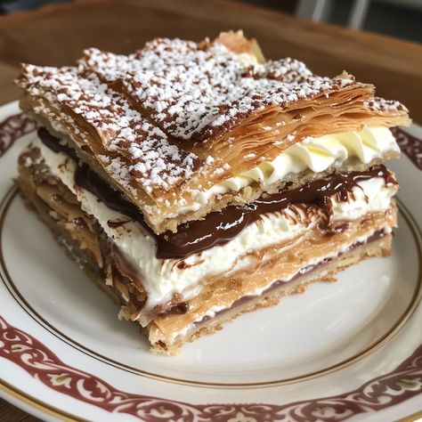 Heavenly Mille-Feuille Ingredients: 1 sheet Puff pastry 250ml Heavy cream 50g Sugar 1 tsp Vanilla extract 100g Dark chocolate, melted Powdered sugar for dusting Instructions: Preheat your oven to 200°C (400°F). Roll out the puff pastry sheet and cut it into three equal rectangles. Place the pastry rectangles on a baking sheet lined with parchment paper. Prick the pastry with a fork. Bake in the preheated oven for 15-20 minutes until golden and puffed. Let the pastry cool completely. In a mi... Chocolate Pastries, Puff Pastry Recipe, Puff Pastry Cake, Chocolate Pastry, Rich Desserts, No Bake Snacks, Pretty Dessert, Food Drink Photography, Food Therapy