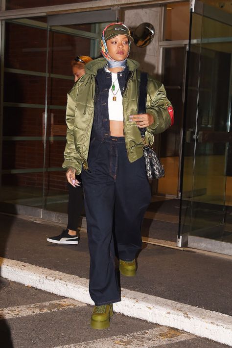 In a Supreme baseball hat, silk scarf, white ribbed crop top, denim jacket and matching oversized jeans, olive puffer jacket and Fenty x Puma boots while out in New York. 90s Chola, 90s Chola Fashion, Western Winter Fashion, Rihanna Street Style, Western Winter, Looks Hip Hop, Looks Rihanna, Rihanna Outfits, Rihanna Looks