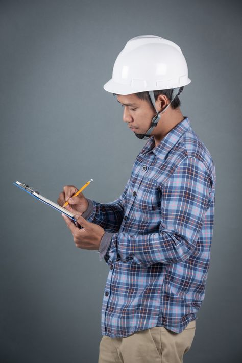 Engineer holding blueprints and reading notes on clipboard while standing on gray background. Holding Clipboard, Funny Baby Gif, Reading Notes, Body Poses, Photo Editing Software, Clipboard, Displaying Collections, Gray Background, Vector Photo