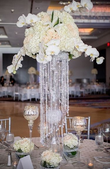 The jewels hanging from this centerpiece really adds an element of elegance. Formal Decorations, Tall Arrangements, White Flower Centerpieces, Pearl Centerpiece, Elegant Centerpiece, Crystal Centerpieces, Wedding Chandelier, Tall Centerpieces, Unique Centerpieces