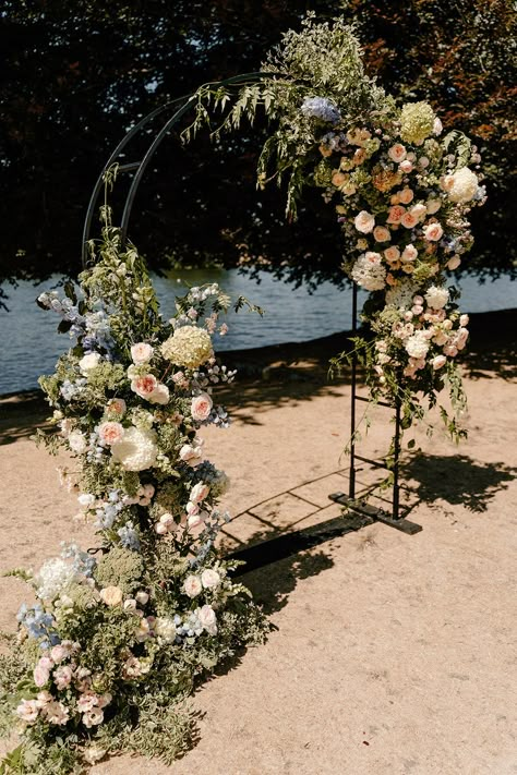 Black steel arch complete with floral decor by the River Thames Garden Arch Wedding, Menorca Wedding, Modern Arch Wedding, Doughnut Tower, Winter Wedding Arch, Dried Petal Confetti, Floral Backdrop Wedding, Flower Arches, Wedding Gate