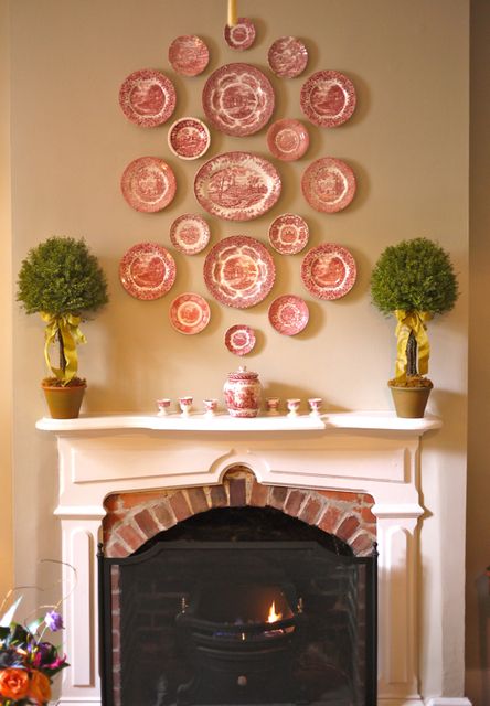 Lovely collection of red and white plates arranged above a mantel. The colors tie them all together though they vary in size and the center one is an oval platter. The topiary trees balance it out and add to the symmetry. Plates On The Wall, Plate Wall Decor, Casa Vintage, Plate Decor, Plate Display, White Plates, Vintage Plates, Vintage China, A Fire