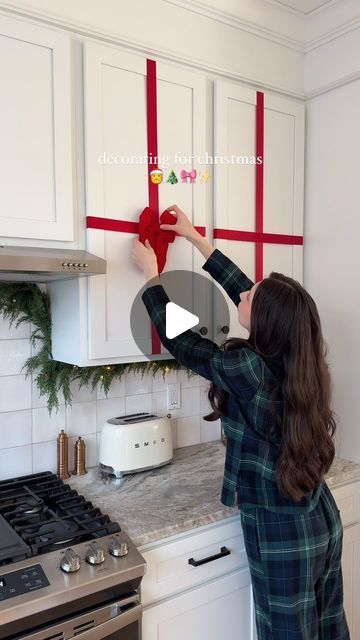 Sheri Wilson on Instagram: "Turning my kitchen cabinets into Christmas presents! 🎀✨   Comment SHOP to receive a DM with the link to shop this post on my LTK ⬇ https://liketk.it/4W7AU  This was easier than I was expecting and I’m absolutely loving the festive vibes! The holidays cannot arrive fast enough this year 😍  I attached the ribbons using clear tape inside the cabinets, then attached a velvet bow to each one. Velcro tabs would probably well for this also!  #christmas #christmasmood #christmasvibes #christmasdecor #cozychristmas #christmaspresents #christmastime" How To Put Bows On Kitchen Cabinets, Bows On Cupboards, Kitchen Cabinet Christmas Decor Ribbons, Wrapping Kitchen Cabinets For Christmas, Cabnit Christmas Bow, Ribbons On Cabinets, Kitchen Christmas Decorations Cabinets Diy, Bow On Kitchen Cabinets, Wrap Cabinets Christmas