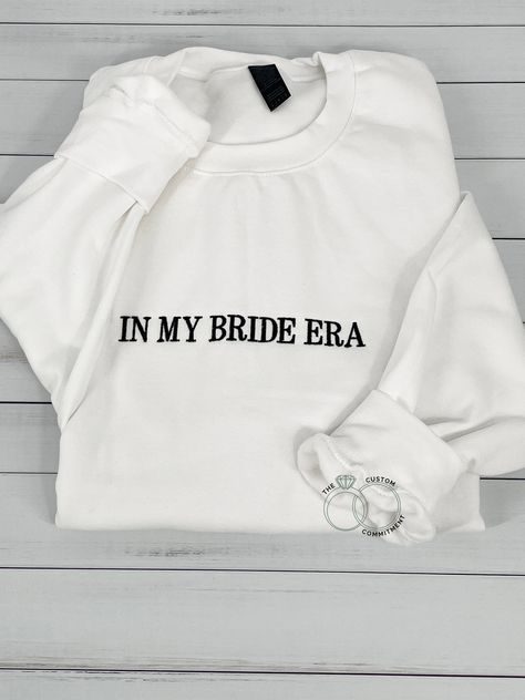 This IN MY BRIDE ERA Crewneck Sweatshirt  It is a great engagement gift, anniversary gift, even wedding gift! It is a great gift for your wife, for your fiance, for a girlfriend. It is also great for a honeymoon trip! Even a bachelorette party! MATCHING GROOM SWEATSHIRT: https://etsy.me/3PAItvF Hoodies and Sweatshirts are MIDWEIGHT and are super soft on the inside! THIS IS A WHITE SWEATSHIRT AND THE WHITE COLOR THREAD.  *Please note that if you order a white sweatshirt with dark stitching some o Bride Sweat Suit, In My Bride Era, Engagement Sweatshirt, Bride Sweats, Destiny Wedding, Bride Crewneck, Bachelorette Party Matching, Bride Era, Gift For Bride To Be