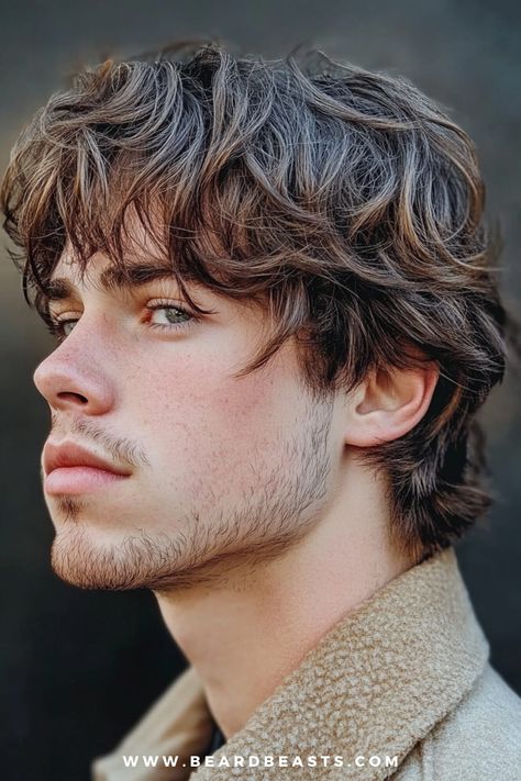 The image features a side profile of a young man with a layered shaggy men’s haircut. His hair is styled in soft, tousled layers that add depth and texture, giving it a natural, windswept appearance. The layers are longer on top, gradually tapering towards the ends, creating a dynamic and voluminous look. His facial hair is light and neatly trimmed, complementing the casual, laid-back vibe of his hairstyle. The background is blurred, ensuring that the focus remains on his men's shaggy hairstyle and its textured, layered finish. This style is perfect for those seeking a trendy yet effortless look. Men’s Shaggy Haircut Short Sides, 70s Shag Haircut Men, Medium Flow Hair Men, Men’s Shaggy Haircut, Mens Haircut Long On Top Short On Sides Medium Lengths, Mens Shag Cut, Longer Haircuts For Men, Shaggy Haircuts For Men, Gavin Haircut