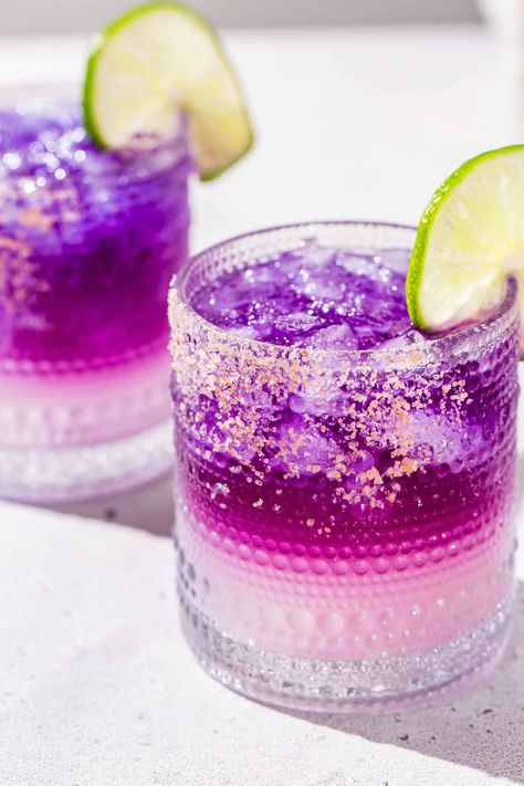 The Galaxy Margarita is as tasty as it is beautiful! Tequila that's naturally colored by butterfly pea flowers is layered on top of a Cointreau and lime base. Edible glitter takes it to the next level! It is a fun galactic spin on a classic margarita. This is the perfect margarita recipe for a girls night, bachelorette or just a night of stargazing! Purple Margarita Recipe, Purple Margarita, Margarita Flight, Perfect Margarita Recipe, Tequila Drinks Recipes, The Perfect Margarita, Butterfly Pea Flowers, Perfect Margarita, Tacos And Tequila