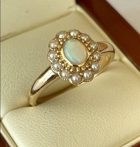 This gorgeous Vintage Inspired Flower Ring has been crafted from 9ct Solid Yellow Gold. A bezel set oval cut NATURAL Opal with surrounding GENUINE Seed Pearls brings this ring to life. Notice the stamens that surround the petals of this beautiful ring. This is an elegant Victorian inspired ring which simply looks beautiful on a lady who enjoys wearing fine jewellery from a Vintage era.  THIS VINTAGE INSPIRED OPAL & PEARL RING IS TRULY AN EXQUISITE FINE JEWELLERY PIECE WHICH IS TO BE TREASURED FO Opal Rings Vintage, Opal Vintage Rings, Vintage Pearl Ring Engagement, Regency Era Rings, Vintage Opal Rings Antique, Vintage Pearl Wedding Ring, Pearl And Opal Engagement Ring, Pearl Engagement Ring Vintage Victorian, Regency Engagement Ring