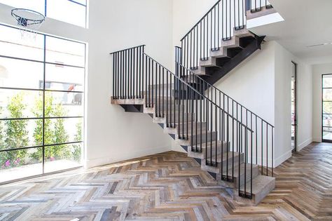 Modern foyer features a rustic wood herringbone floor which leads to an iron and reclaimed wood staircase. Modern Mediterranean Exterior, Spanish Transitional, Rustic Foyer, Herringbone Floors, Entrance Foyer Design, Steel Staircase, Steel Frame Doors, Modern Mediterranean Homes, Modern Foyer