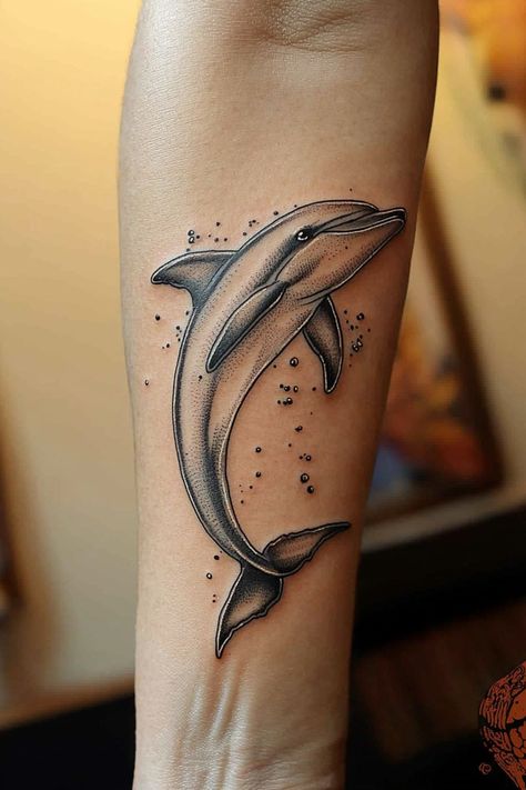 A black and gray dolphin tattoo on a woman’s arm, offering a classic and refined design with gentle shading. Dolphin Tattoos For Women, Elegant Arm Tattoos, Dolphin Tattoo For Women, 3 Birds Tattoo, Tattoos For Women Arm, Jeep Tattoo, Dolphin Tattoo, Bird Tattoos For Women, Unique Tattoos For Women