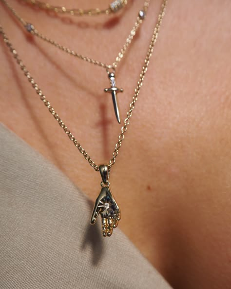 Designed with an asymmetrical accent stones and a dagger-shaped pendant, you're sure to feel fierce with Maria. Wear it on its own or layer it with other necklaces to create a stunning look. 14k gold plated brass and palladium base Chain length 17” + 2” extender Sword charm measures approx 18mm x 6mm Accented with clear cubic zirconia Coated for long-wearing protection Gothic Gold Jewelry, Maria Necklace, Styled Jewelry, Classic Pendant Necklace, Dagger Necklace, Protection Jewelry, Edgy Jewelry, Hand Necklace, Pierced Jewelry