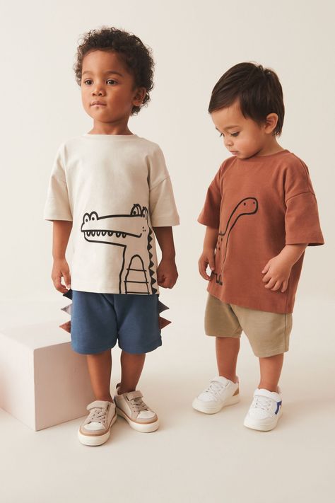 This stylish 2-piece t-shirt and shorts set features a rust brown dinosaur t-shirt and blue jersey shorts with 3D dinosaur scales along the side hem, alongside an ecru cream crocodile t-shirt with coordinating neutral shorts, crafted from pure cotton. The tops boast a drop shoulder and crewneck collar, whilst the shorts have an adjustable elasticated waistband. T-shirt CEMENT, T-shirt RUST, Shorts BLUE and Shorts CEMENT 100% Cotton. Baby T Shirt, Kids T Shirts, Boys Clothing, Kids Tshirt, Printed Shirts For Boys, Kids Boys Shirts Style, Boys T-shirt Print, Boys Summer Shirts, Kidswear Trends