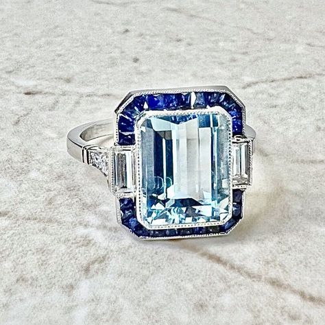 Breathtaking handcrafted platinum Art Deco style aquamarine, sapphire and diamond halo cocktail/engagement ring! It is set with a fine emerald cut aquamarine weighing 3.23 carats (10.02 x 8.07 mm). It is haloed by a row of natural French cut blue sapphires weighing approximately 1/2 carat. It is accented by 2 baguette diamonds and 6 old European cut diamonds weighing approximately 0.35 carat. Fine milgrain add to the delicacy of the ring. Beautiful openwork filigree decorate the under gallery. L: 14.05 mm W: 13.34 mm Band width: 1.78 mm Ring size 6.5 US / M 1/2 UK / 52 3 /4 FR. This ring is part of the Authenticity Guarantee program of eBay. For this reason we are unable to resize if bought on eBay. Please visit our website WeiLJewelry to purchase and resize this ring. Birthstone: March/Ap Art Deco Sapphire Ring, Diamond Halo Ring, Aquamarine Engagement Ring, Aquamarine Jewelry, Aquamarine Rings, Deco Jewelry, Halo Diamond Ring, Art Deco Diamond, Custom Jewelry Design