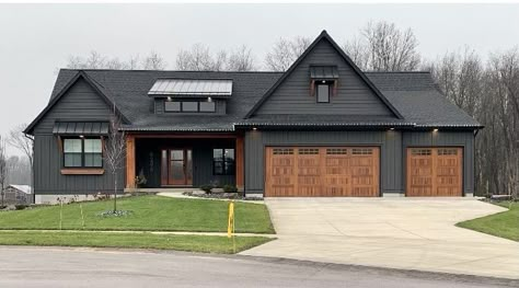 Black House Siding Ideas, Dark Gray Black Trim House Exterior, Dark Grey House Wood Door, Black Vertical Siding Exterior, Dark Mobile Home Exterior, Ranch Style Black House, Black House With Wood Trim, Dark Gray House Deck Color, Black Rambler House Exterior