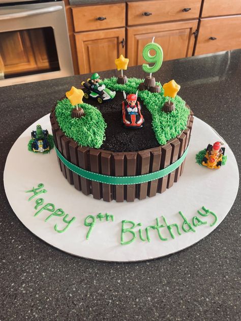 Mario Kart KitKat Cake…8 inch round cake, add frosting to sides then placed kitkats around lightly tied with ribbon to keep in place. Green grass piped frosting, oreo crumble for road mini reeses for yellow chocolate star stands. Mario Kart toys for decoration purchased at Walmart. Easy Super Mario Birthday Cake, Mario Cart Cakes Birthday Easy, Easy Mario Cake Ideas, Mario Kart Cupcake Cake, Super Mario Round Cake, Mario Kart Cake Buttercream, Mario Cake Decorations, Super Mario Chocolate Cake, Super Mario Bros Cake Easy