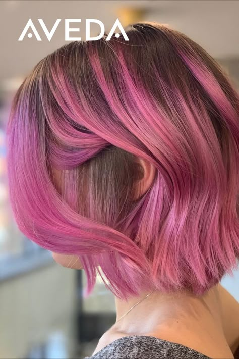 You can show off a glam hairstyle and accentuate your colorful side with this wavy, pink bob hairstyle. Keep a shadow root for a sophisticated hair melt. Beyond the spectrum of vibrant colors an Aveda Artist can hand-create for you, are so many different techniques and placements to choose from. Click to find the look you love. Aveda Artist @minhwaleehair #GlamHair #PinkHair #ShortHair #HomecomingHair #AvedaVibrantColor #ShortHairIdeas #HairInspo Fashion Color Bob Hair, Colored Hair With Natural Roots, Short Pink Bob Hairstyles, Pink Hair Natural Roots, Short Shadow Root Hair, Colorful Hair Dark Roots, Rooty Pink Hair, Short Pink Hair Dark Roots, Chin Length Hair For Thinning Hair