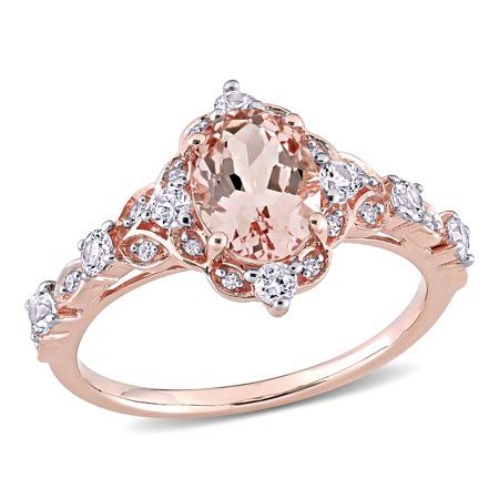 This intricately designed Miabella Vintage Halo Ring is the epitome of beauty and grace. Crafted in lustrous rose gold, this sophisticated ring features an oval-cut prong-set morganite gemstone (8x6mm) encased in a beautiful halo design created by eight round-cut prong-set white sapphire gemstones (2.25x2.25mm)(2x2mm) and 16 round-cut pave-set diamonds (G-H, I1-I2). Enhanced with a polished finish, this classic ring is perfect for a quick glam fix. This classic and sparkling piece is indeed a ti Verragio Engagement Rings Rose Gold, Rose Gold Halo Ring, Vintage Halo Ring, Rose Gold Oval Engagement Ring, Verragio Engagement Rings, Pretty Engagement Rings, Vintage Halo, Cute Engagement Rings, Future Engagement Rings