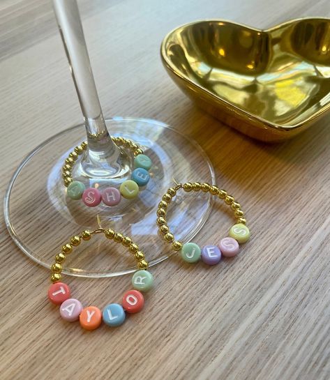 These beaded wine charms are adorable! 💕 Planning my wedding and thinking these would make the cutest bridesmaids' gifts ever! Each one personalized with their names – such a thoughtful touch! Can't wait to add these to my wedding party goodies! Diy Wine Charms, Wine Glass Charms Diy, Diy Wine Glass Charms, Name Tag Wine Glasses, Wine Glass Name Tags, Wine Charms Diy, Bridesmaids Gift Ideas, Personalized Wine Glass Charms, Bride Era