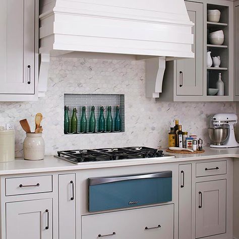 Tuck an alcove between studs and behind the range, then line it with tile to create a kitchen backsplash that doubles as storage. In this kitchen, dressed in soothing gray and blue, hexagonal marble tile and blue linear glass tile converge behind the cooktop for a one-of-a-kind backsplash idea./ Backsplash Options, Honeycomb Backsplash, Backsplash Inspiration, Hex Tiles, Kitchen Tile Backsplash, Subway Tile Backsplash Kitchen, Unique Kitchen Backsplash, Niche Market, Diy Kitchen Backsplash