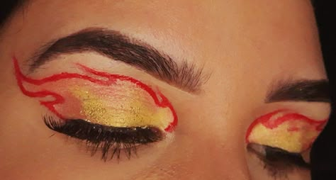 Olhos com uma chama de fogo desenhado em vermelho, com sombras laranja e amarelo dentro do formato, com glitter amarelo e cílios postiços Fireball Makeup Looks, Fire And Ice Makeup Halloween, Flame Outfit Aesthetic, Firefighter And Flame Costume, Fire Flame Costume, Flame Princess Makeup, Flame Halloween Costume, Flames Makeup Look, Rengoku Makeup Inspired