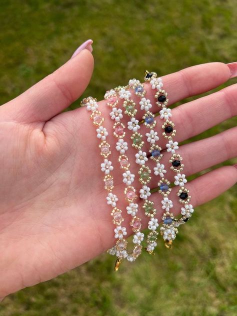 Handmade Beaded Flower Bracelet with gold colour findings. Adjustable Daisy bracelet with coloured bead available in five variations: -Clear -Pink -Green -Blue  -Black Please select your chosen colour from the menu when placing your order. Bracelet fits sizes between 16-19cm with use of extender chain. Please note some threads may be visible as this is a handmade product. Ensure to keep this piece out of water and avoid contact with fragrances and lotions as this can make the colours fade. Please drop me a message if you have any special requests regarding colouring and sizing and I will do my best to accommodate these! Bracelets are carefully presented on card display to ensure that they arrive in perfect condition. Bracelet Handmade Ideas, Daisy Beads Bracelet, Bracelet Cards, Flowers Bracelets, Bead Bracelet Patterns, Flower Bead Bracelet, Daisy Chain Bracelet, Daisy Flower Bracelet, Beaded Bracelets Handmade